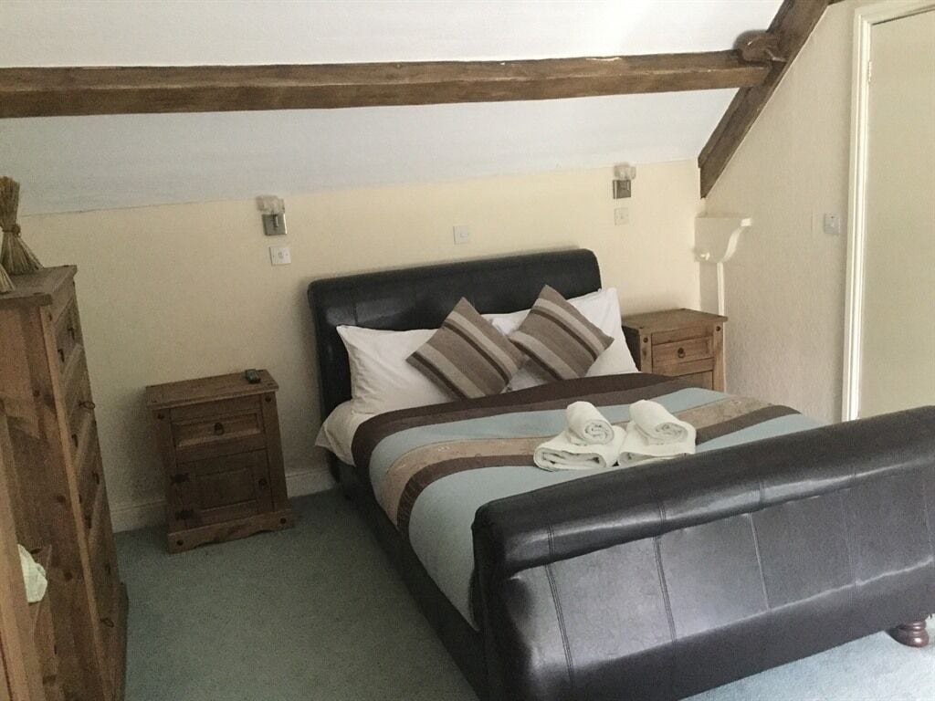 Une chambre à coucher avec un lit, des tables de chevet en bois et une tête de lit.