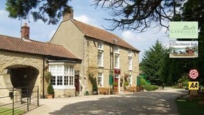 A traditional stone building with a sign for 'The Coachman Bar' and 'Carriages'. - The Coachman Inn (Scarborough)