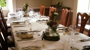 A long dining table set with multiple place settings, including plates, cutlery, and wine glasses. - The Coachman Inn (Scarborough)