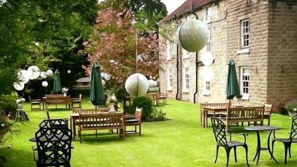 A courtyard with outdoor seating, a stone building, and a well-maintained lawn. - The Coachman Inn (Scarborough)