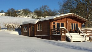 A wooden cabin with a covered porch and a small staircase leading to a deck. - Long Mountain Centre (Shrewsbury)