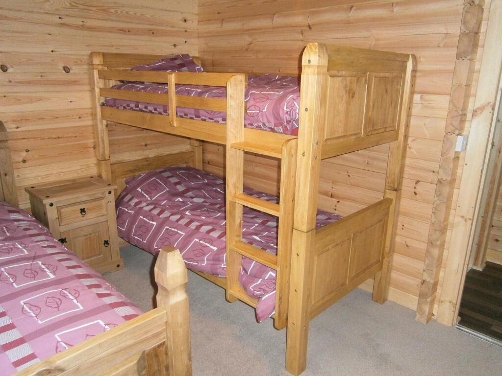 A bunk bed with a wooden frame and a patterned bedspread.