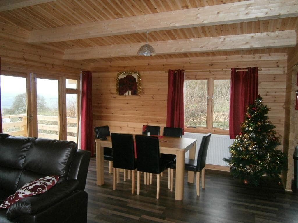 Un interno in legno con un tavolo da pranzo, sedie, un albero di Natale e un divano.