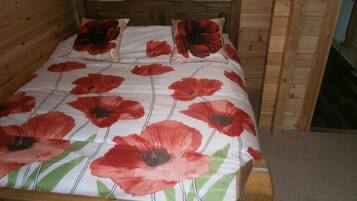 A wooden bed with a poppy-patterned bedspread and pillows.