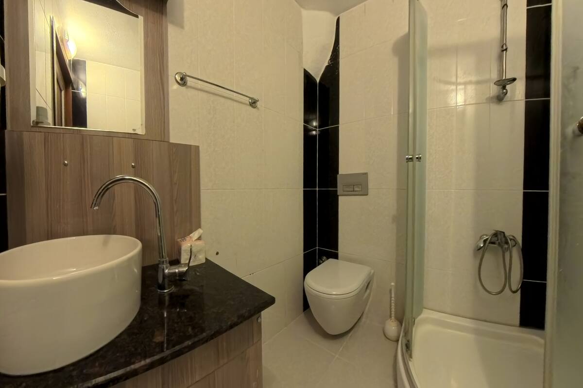 Un baño moderno con lavamanos, inodoro y ducha.