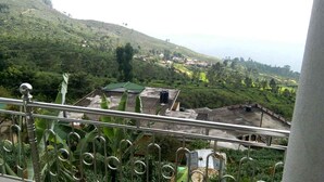 A view from a balcony overlooking a lush green valley with terraced fields and scattered buildings. - Amaya View Guest Inn (Haputhale)