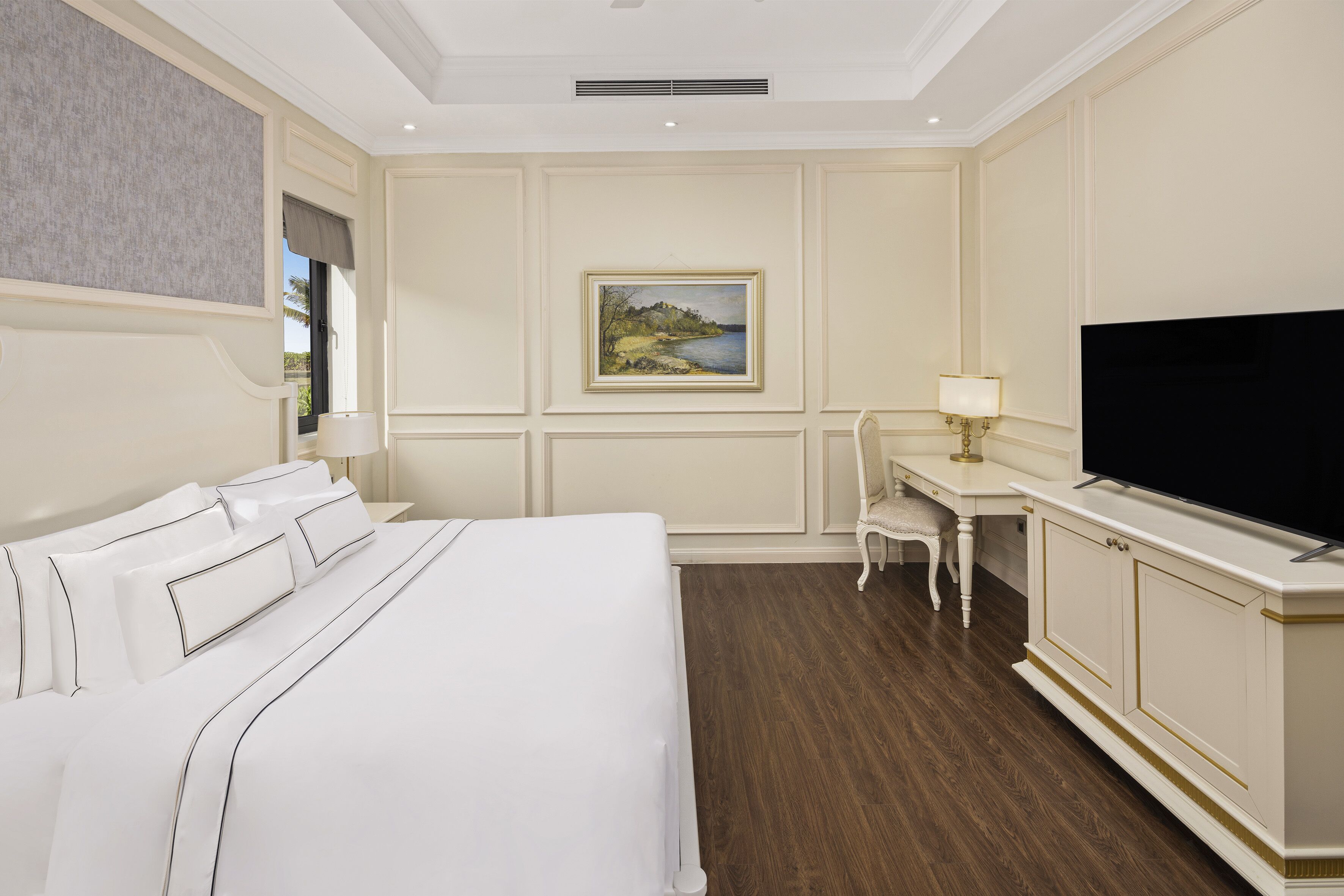 A hotel room with a large bed, a desk with a chair, a television, and a painting on the wall.