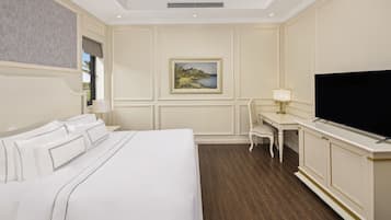 A hotel room with a large bed, a desk with a chair, a television, and a painting on the wall.