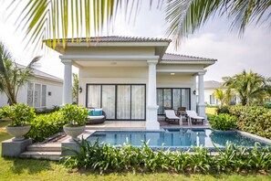 A modern poolside area with a pool, lounge chairs, and potted plants. - Vinpearl Cua Hoi, Affiliated by Meliá (Cua Lo)