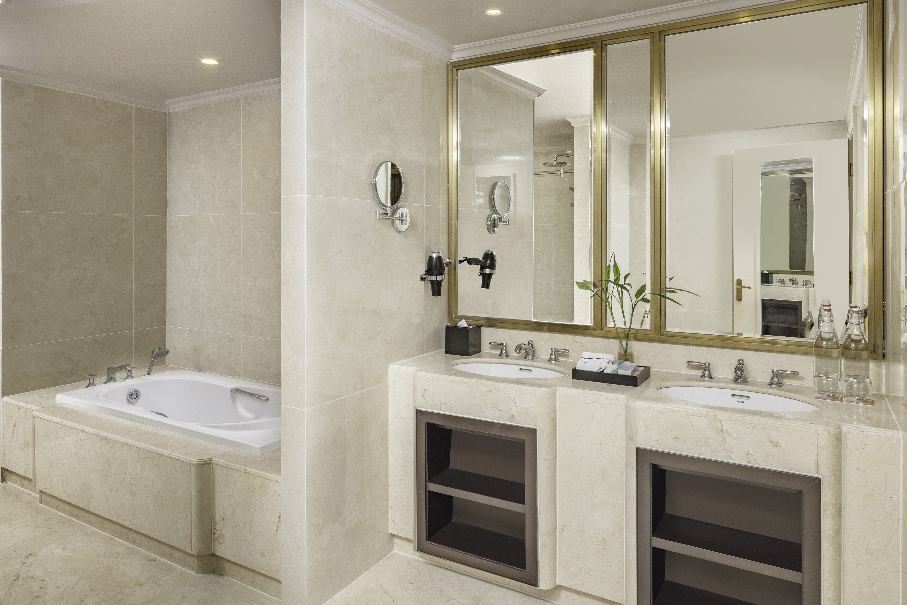 Un baño moderno con dos lavamanos, un espejo grande y una bañera.