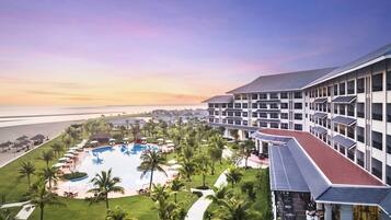 Overlooking the ocean, this resort offers a pool area with lounge chairs and lush surroundings.