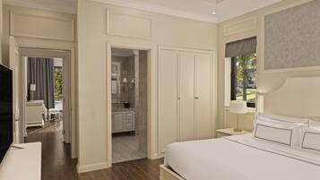 A bedroom with a large bed, a nightstand, a TV, and a bathroom visible through an open door.