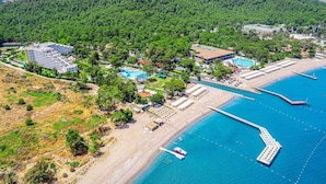 Vue aérienne d’une station balnéaire comprenant plusieurs bâtiments, une plage et une jetée.