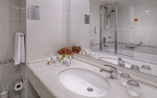 Ένα σύγχρονο μπάνιο με έναν μεγάλο νιπτήρα, ένα γυάλινο διαχωριστικό για την καμπίνα ντους και έναν καθρέφτη που αντανακλά την περιοχή του ντους.