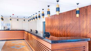 A reception area with a wooden reception desk, multiple pendant lights, and a patterned floor.