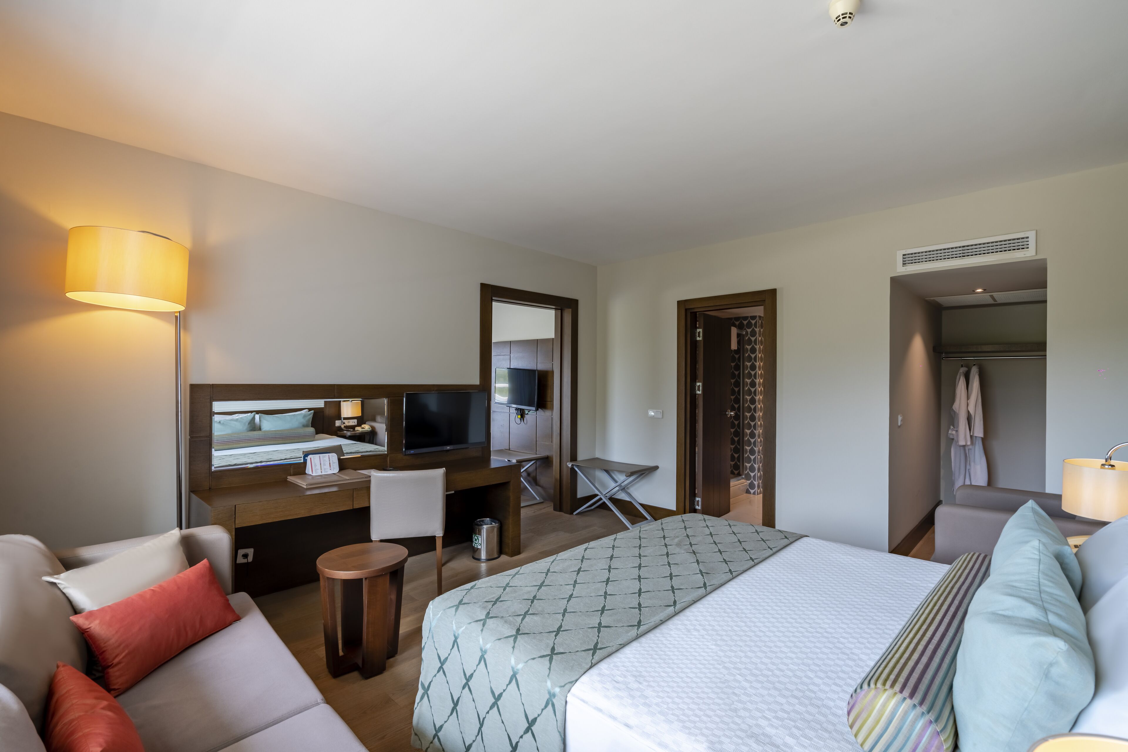 Une chambre d’hôtel comprenant un lit, un bureau avec un ordinateur, une télévision, un canapé et une lampe.