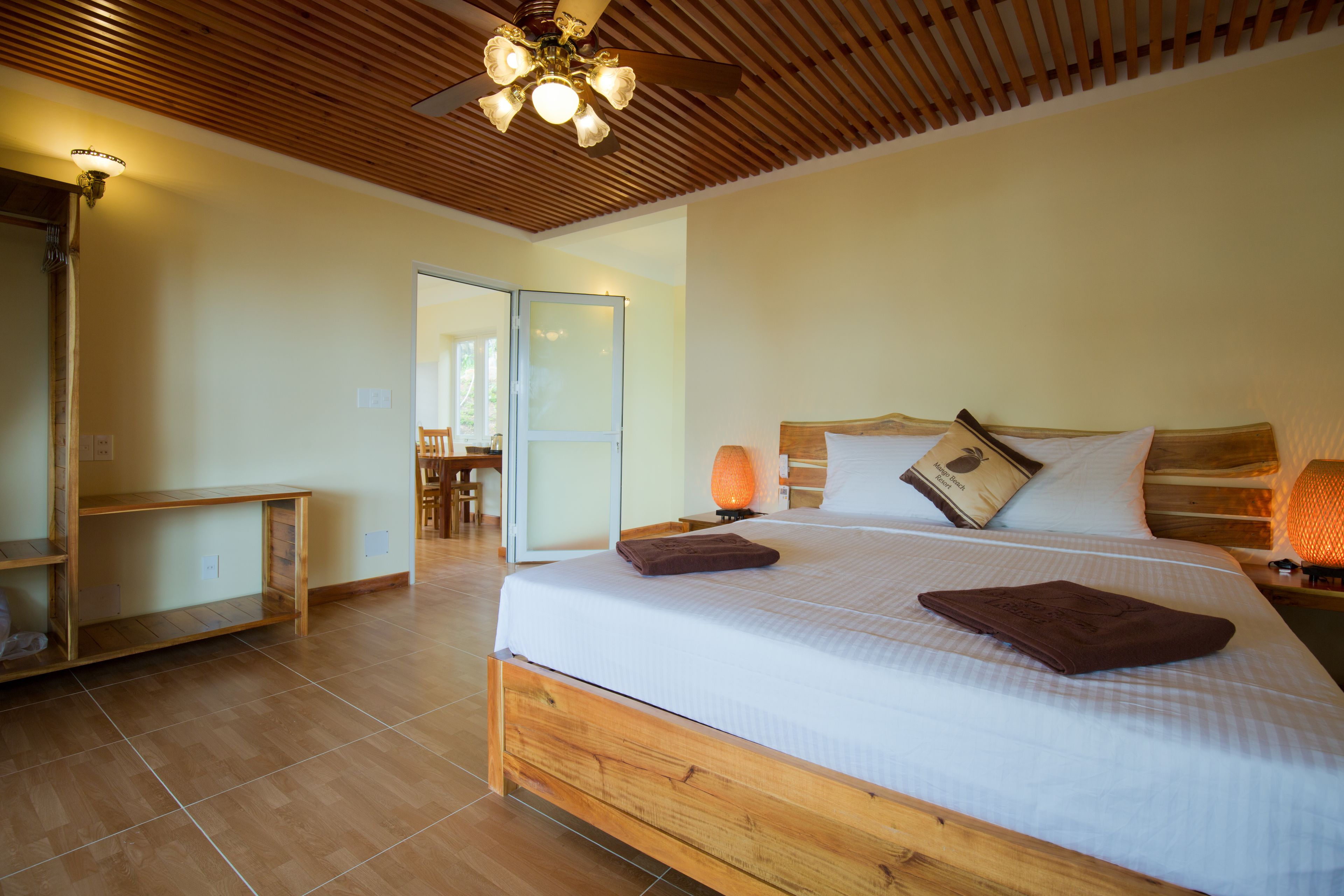 A spacious bedroom with a large bed, wooden headboard, and a ceiling fan.