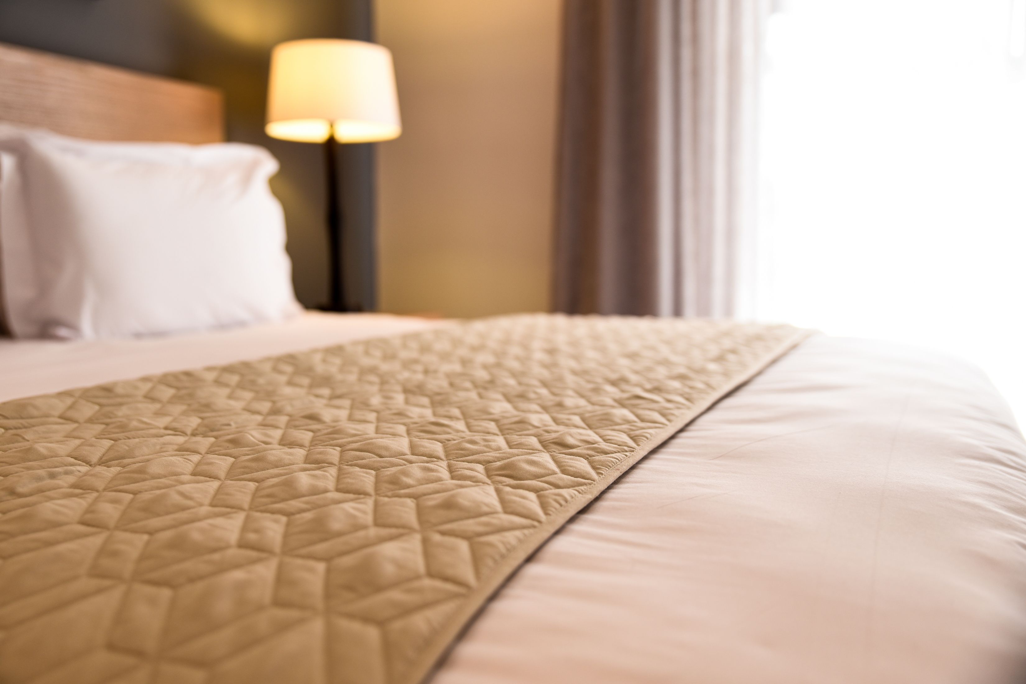Un gros plan d’un lit avec une couverture à motifs et un oreiller uni.