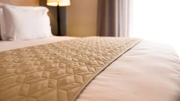 A close-up of a bed with a textured quilt and a plain pillow.