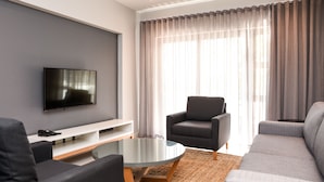 A modern living room with a flat-screen TV, a glass coffee table, and a sofa.