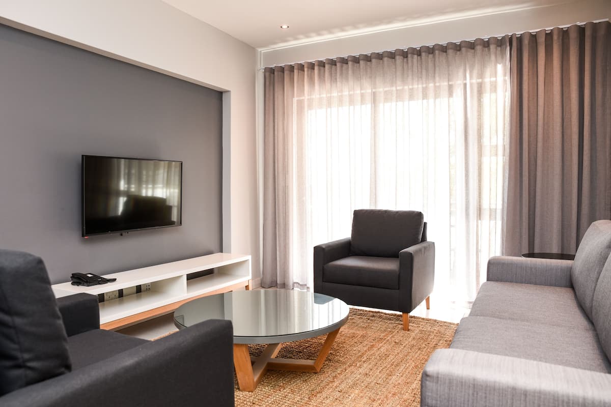 A modern living room with a flat-screen TV, a glass coffee table, and a sofa.