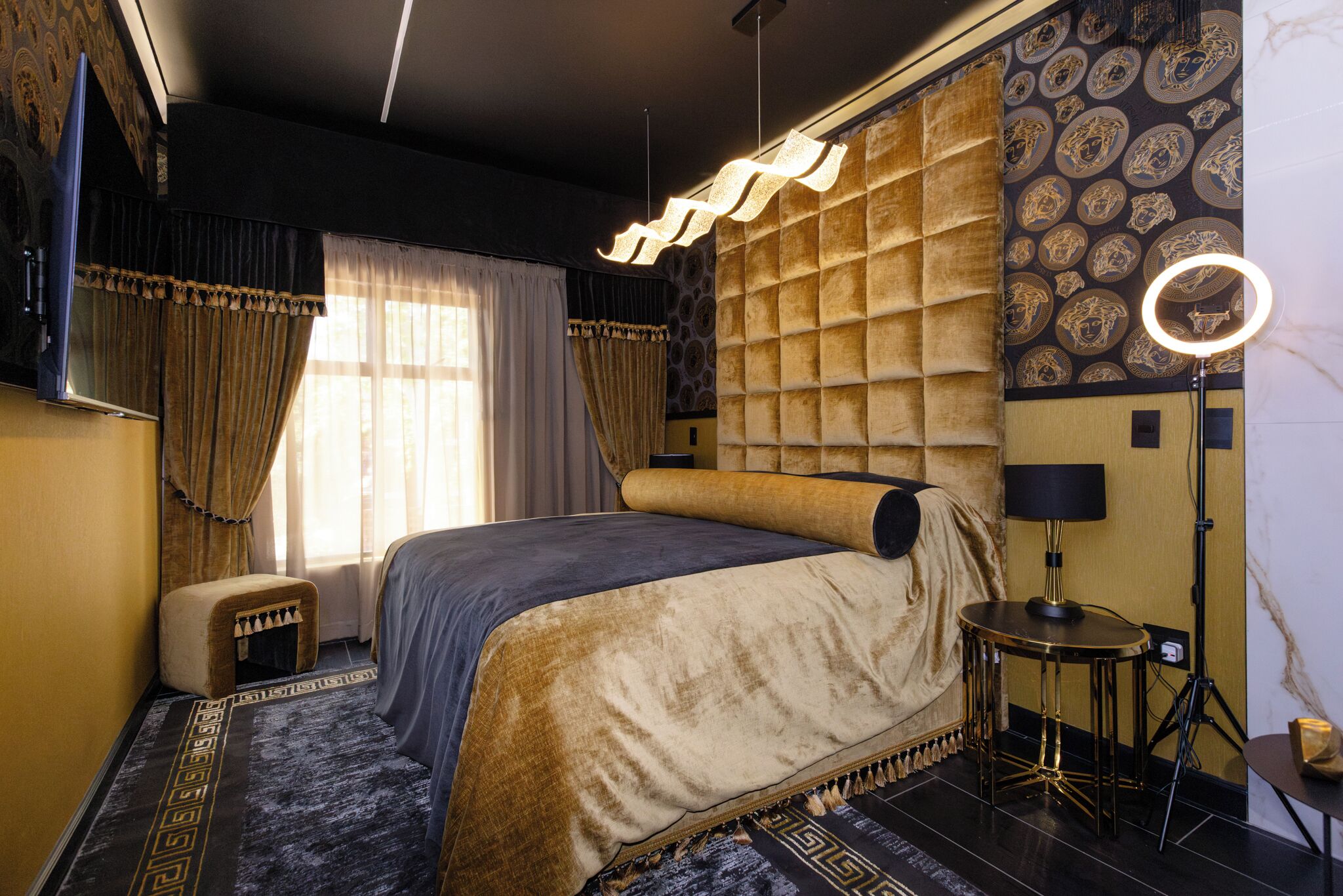 A modern hotel room with a large bed, a vanity with a mirror, and a small stool.