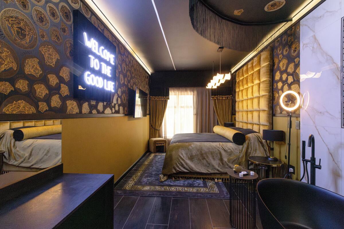 A modern hotel room with a large bed, a desk, and a seating area.