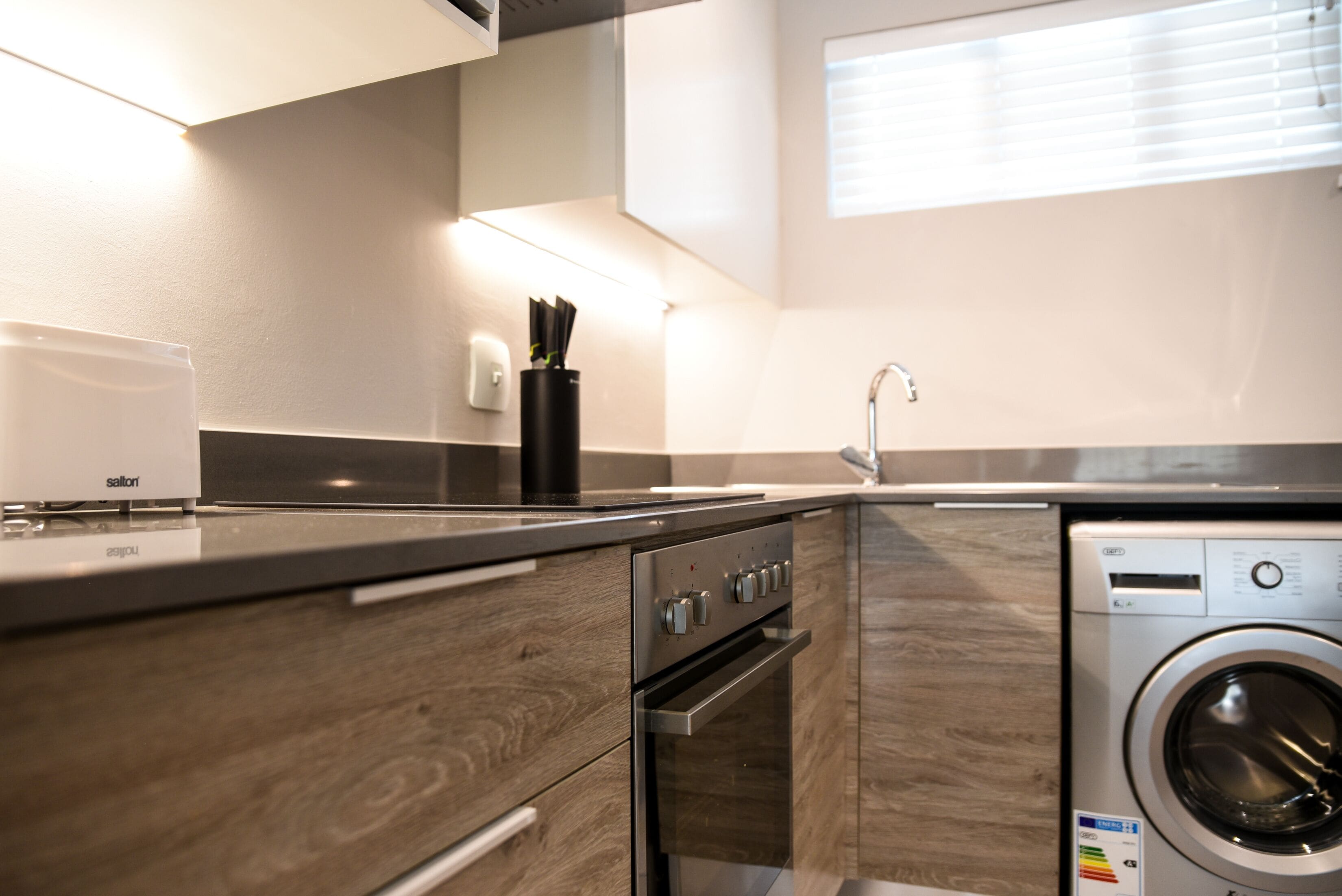 A modern kitchen with a built-in oven, microwave, and washing machine.