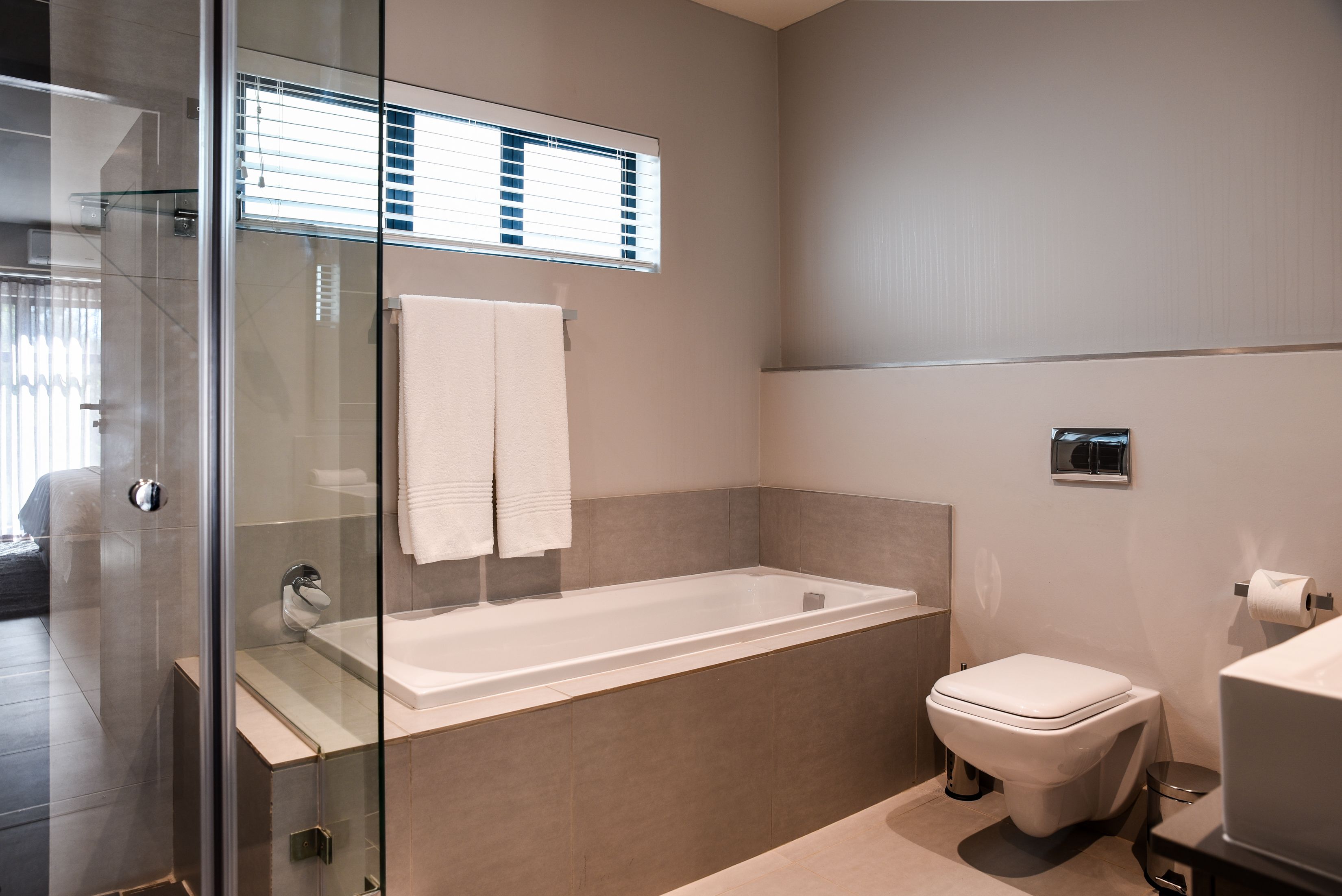 A modern bathroom with a glass shower enclosure, a bathtub, and a toilet.