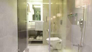 A modern bathroom with a glass-enclosed shower, a toilet, and a sink with a towel rack.