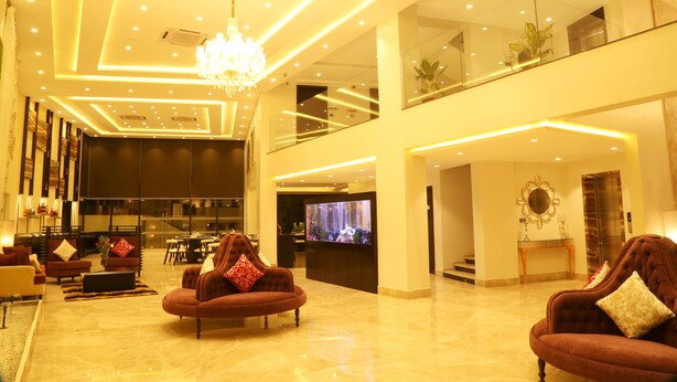 A spacious lobby with a chandelier, a television, and multiple seating areas. - The Flora Grand (Vasco da Gama)