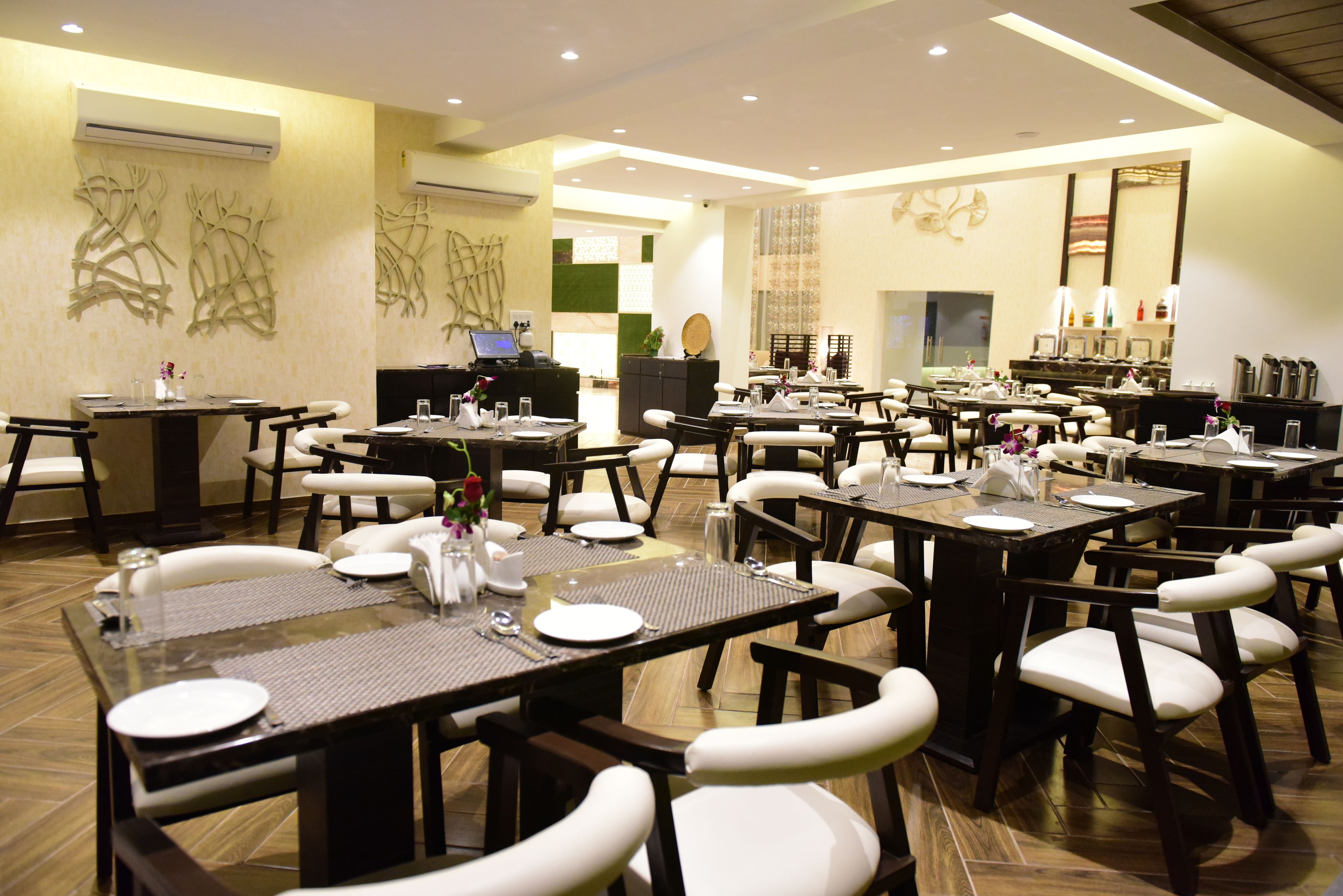 A restaurant with multiple dining tables and chairs, air conditioning units on the walls, and a counter area.