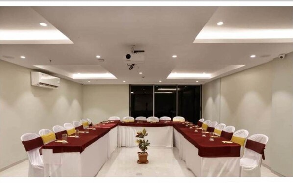 A conference room with a long table, white chairs, and a potted plant.