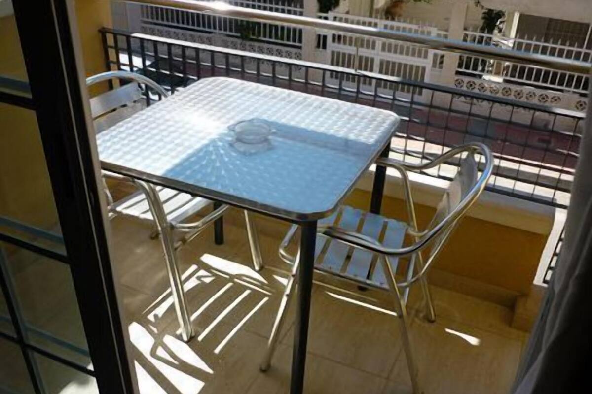 Ein Balkon mit einem Metalltisch und -stühlen, einer Fliesenreling und Blick ins Freie.