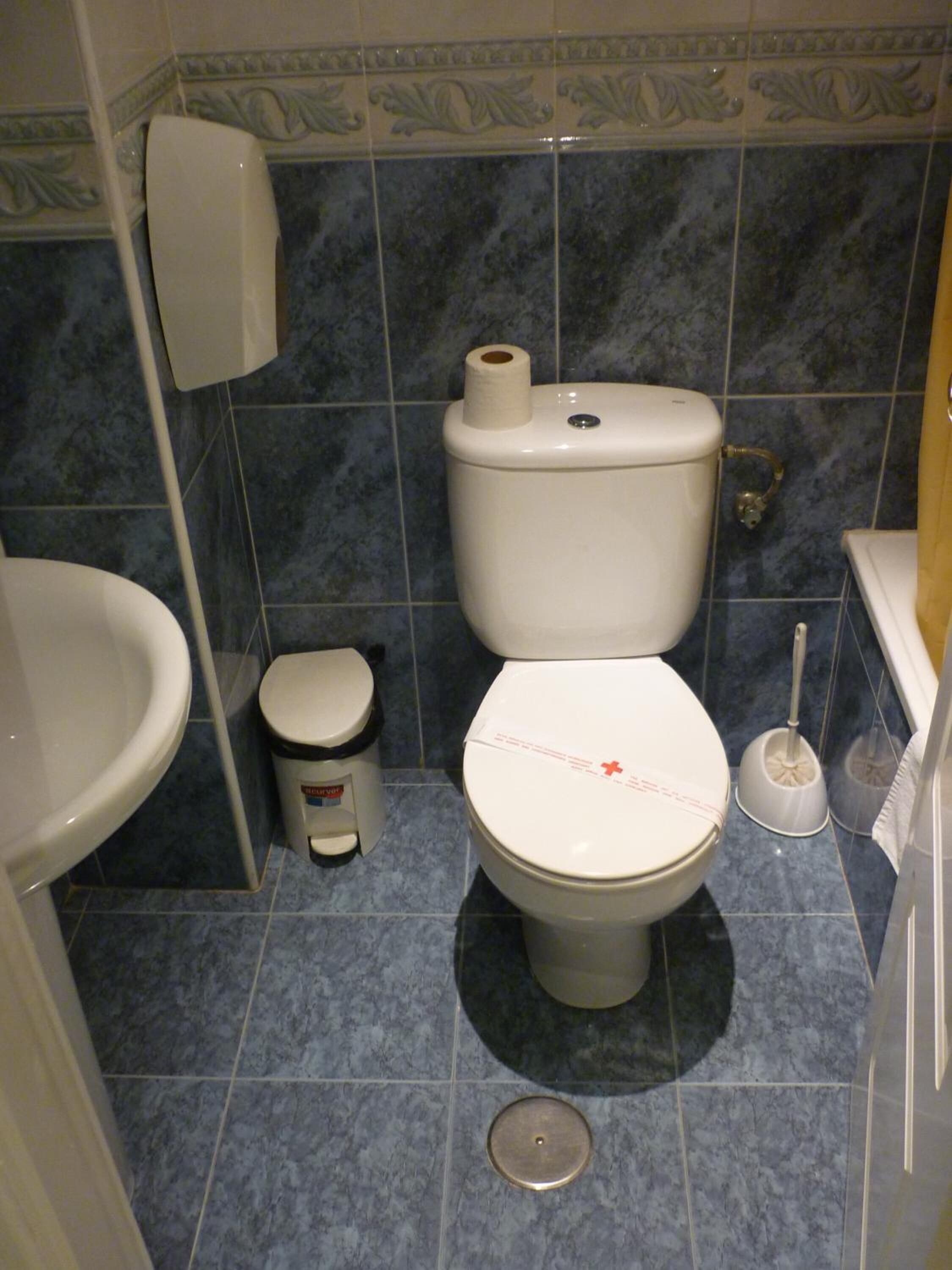 A bathroom with a toilet, bidet, and a trash bin.