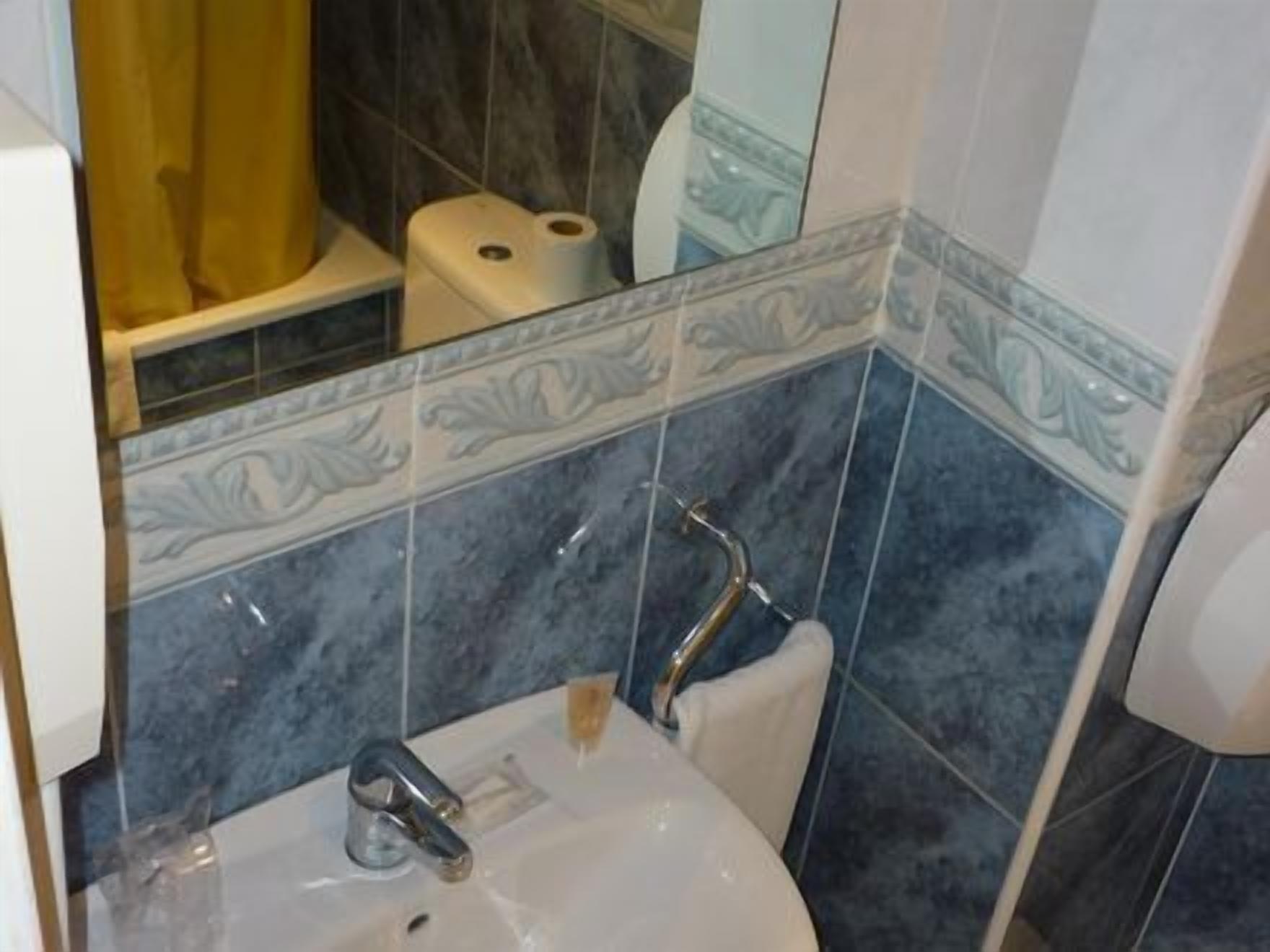 A bathroom with a sink, mirror, and toilet.