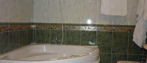 Un baño con bañera, inodoro y una toalla colgada en la pared.