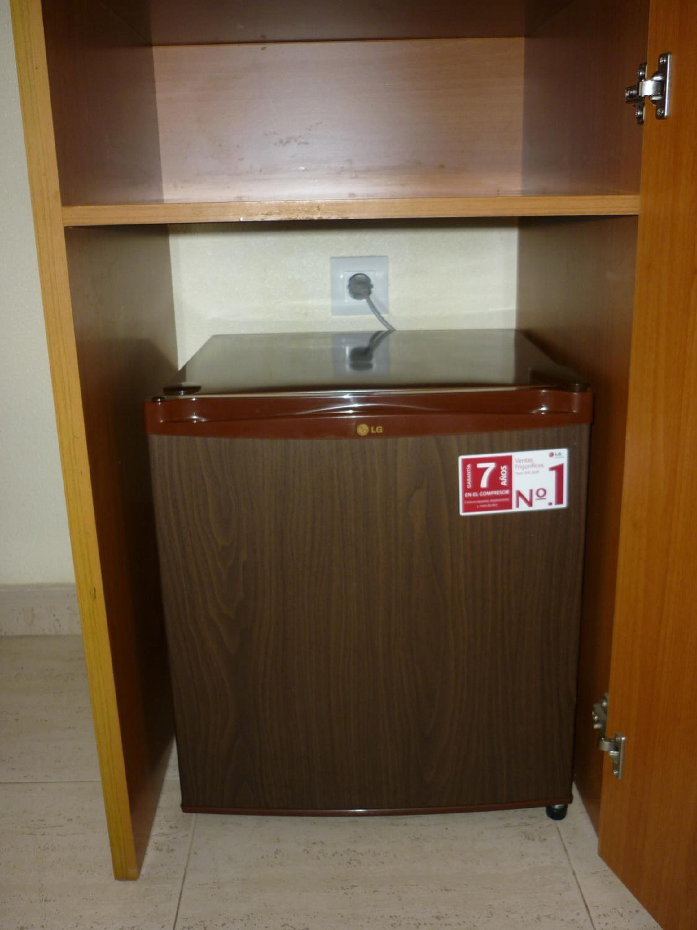 Un refrigerador compacte amb acabat de fusta, un panell de control i un adhesiu que indica que és la primera unitat d'una sèrie.