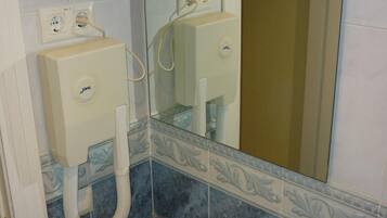 A bathroom with a sink, mirror, and two wall-mounted soap dispensers.