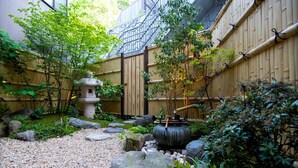 A traditional Japanese garden with a stone lantern, bamboo fence, and a koi pond. - Kazueya (Kanazawa)