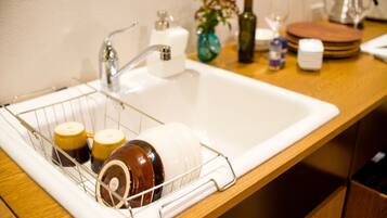 A kitchen sink with a dish rack holding mugs and a bottle.