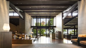 A spacious lobby with a high ceiling, large windows, and a central staircase. - Hoshino Resorts KAI Aso (Kokonoe)