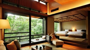 A modern hotel room with a large window, a sofa, a coffee table, and a bed with two pillows. - Hoshino Resorts KAI Aso (Kokonoe)