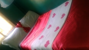 A bed with a red and white bedspread and a pillow with a red bow. - Sammarays Lodge (Nairobi)