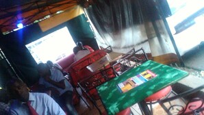 A restaurant interior with red chairs and a green table, a tiled floor, and a visible menu on the table. - Sammarays Lodge (Nairobi)