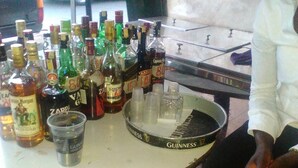 A bar area with a round table displaying various liquor bottles and a Guinness branded coaster. - Sammarays Lodge (Nairobi)