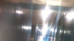 A corridor with checkered flooring, wooden walls, and a bright light source at the end. - Sammarays Lodge (Nairobi)