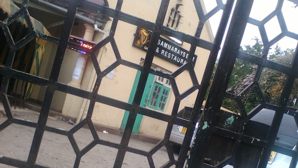 A metal gate with a hexagonal pattern, a sign for 'Sammarayse & Restaurant', and a vehicle parked behind it. - Sammarays Lodge (Nairobi)