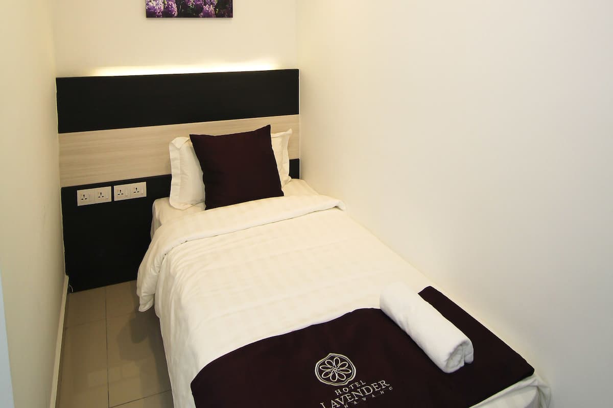 A neatly made bed with a white and maroon bedspread, a pillow, and a folded towel on the side.