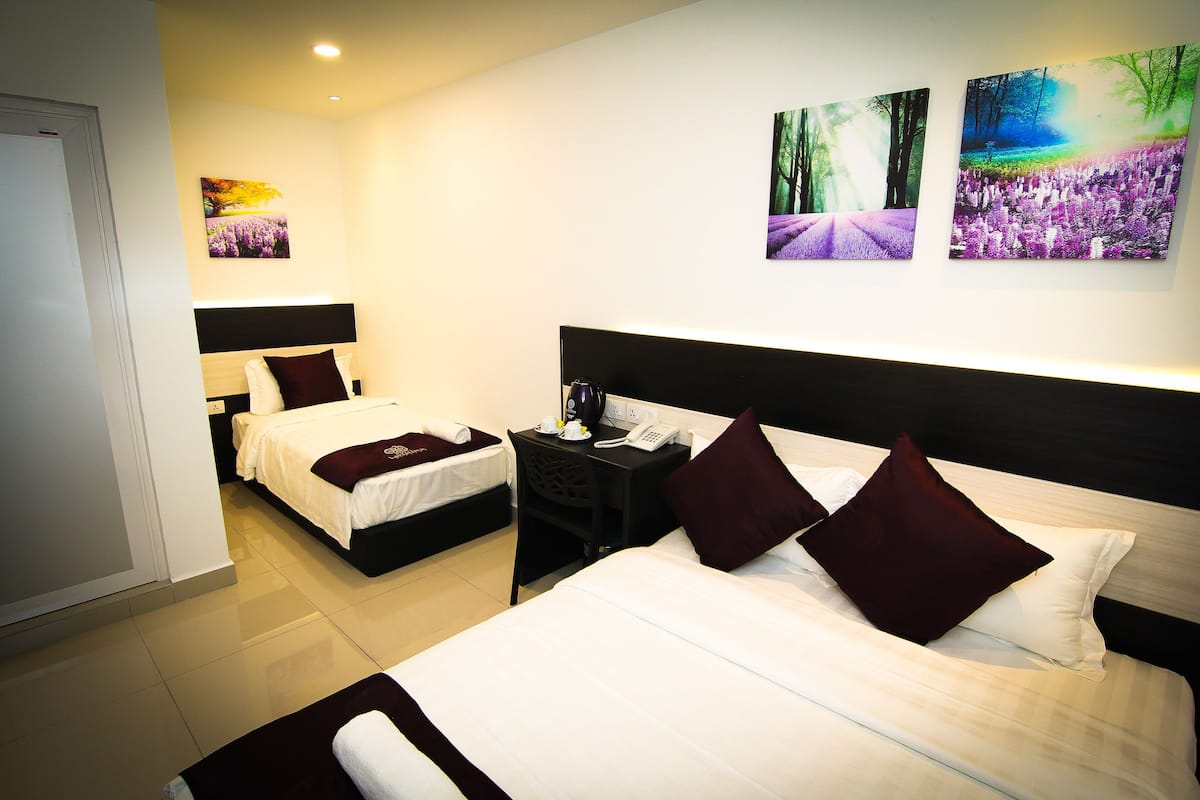 A hotel room with two beds, a nightstand, a telephone, and artwork on the walls.